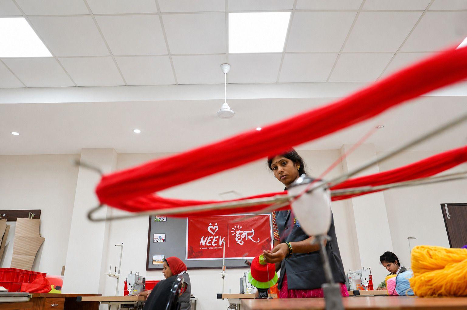 Woman in a bright workshop meticulously working with vibrant red fabric on a processing line.