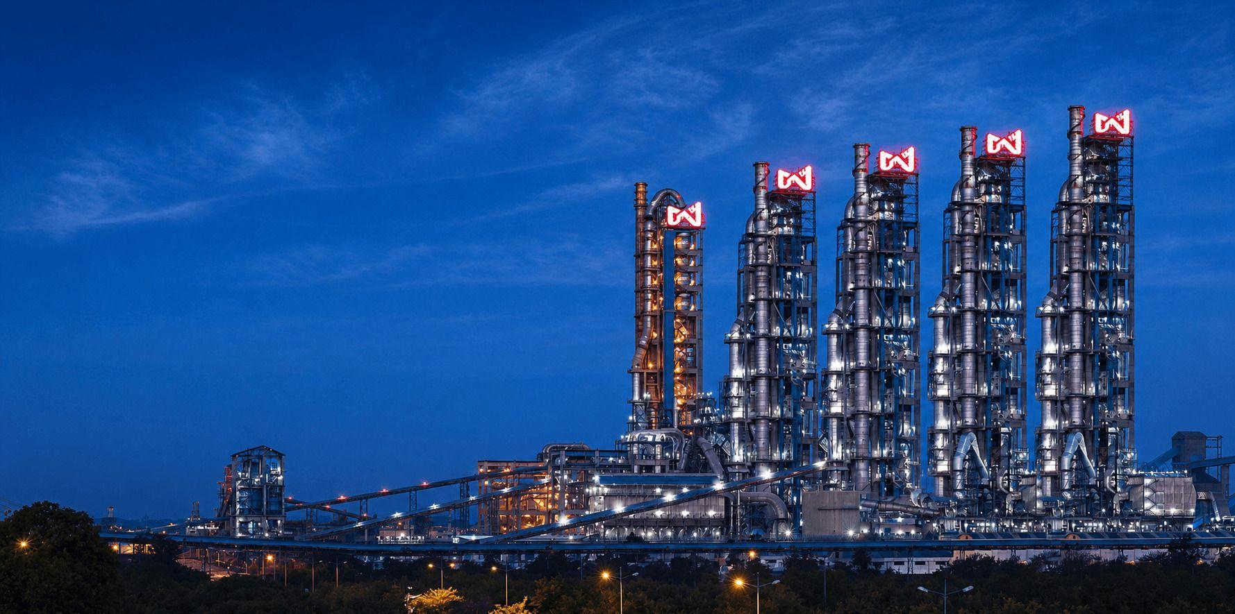 A modern industrial plant with tall, glowing towers against a deep blue night sky.