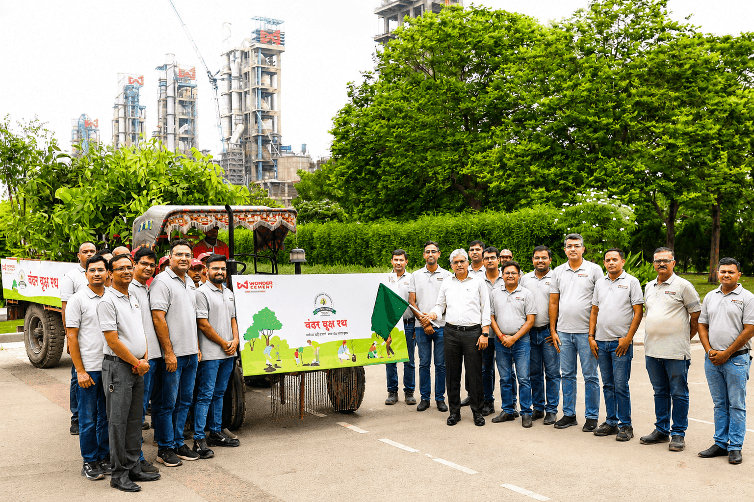 Team of men stand with a banner promoting an environmental initiative outside an industrial complex.