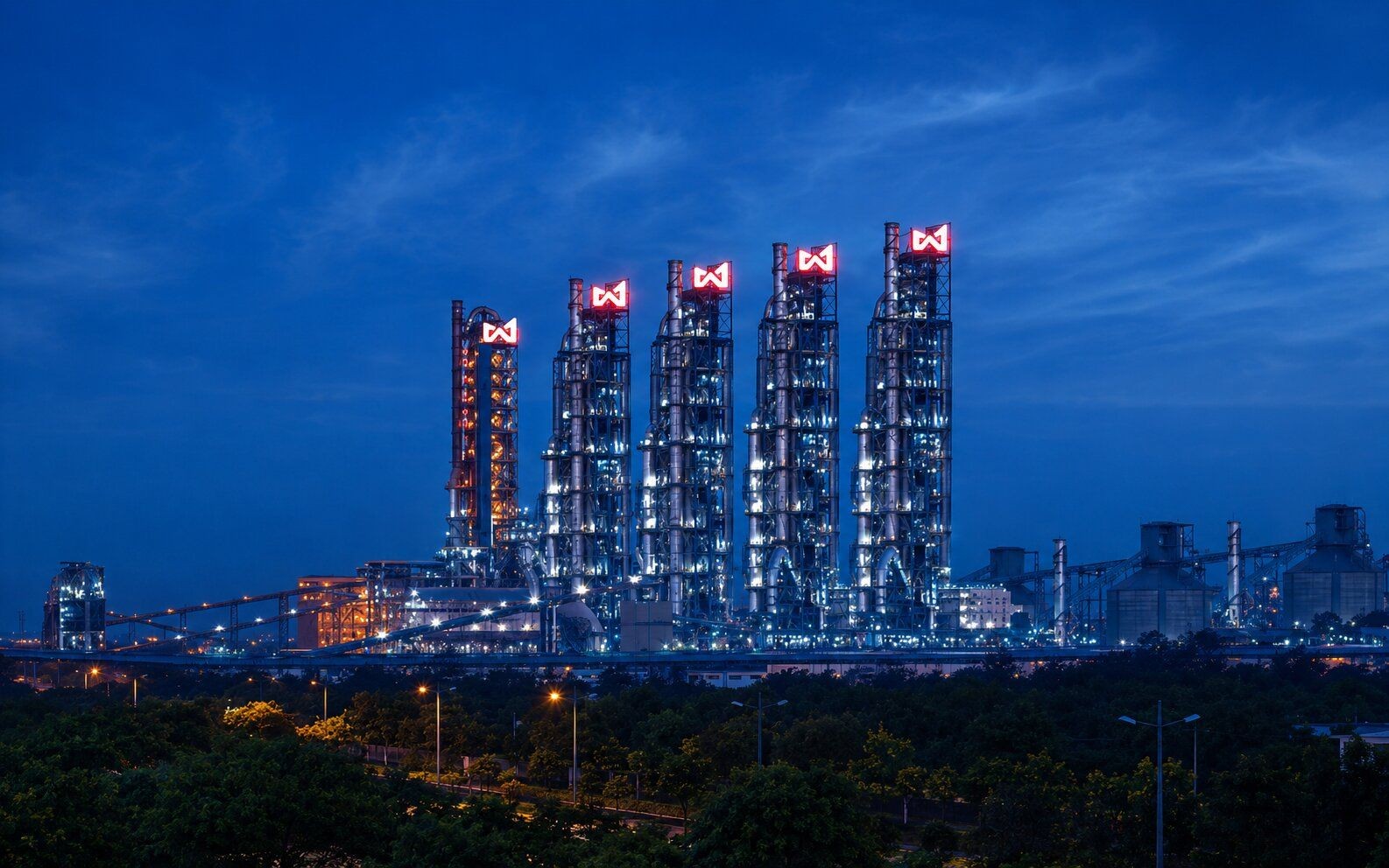 Five modern skyscrapers with glowing red M logos against a dark blue night sky.