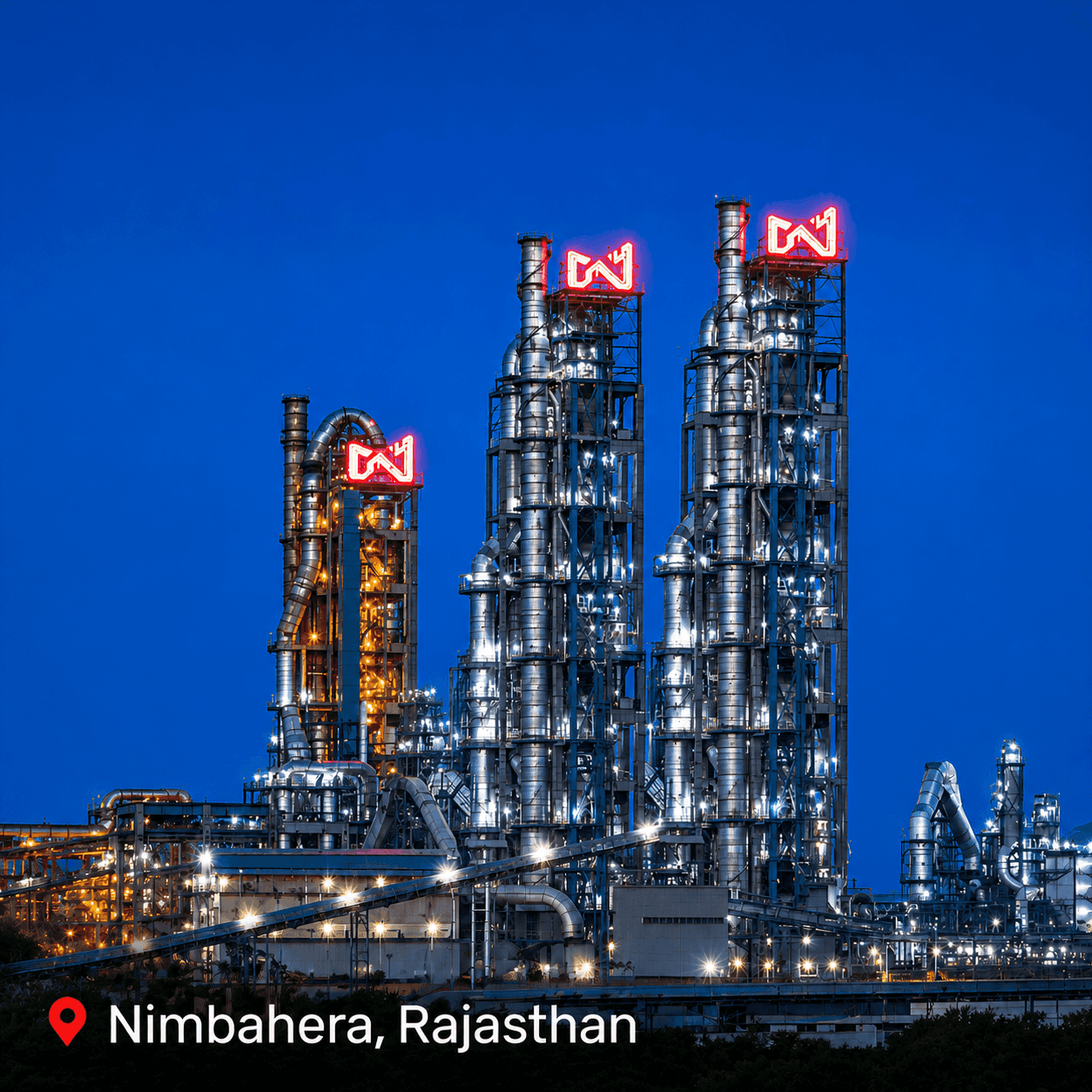 Large industrial plant at night with tall, lit structures and prominent 'W' logos.
